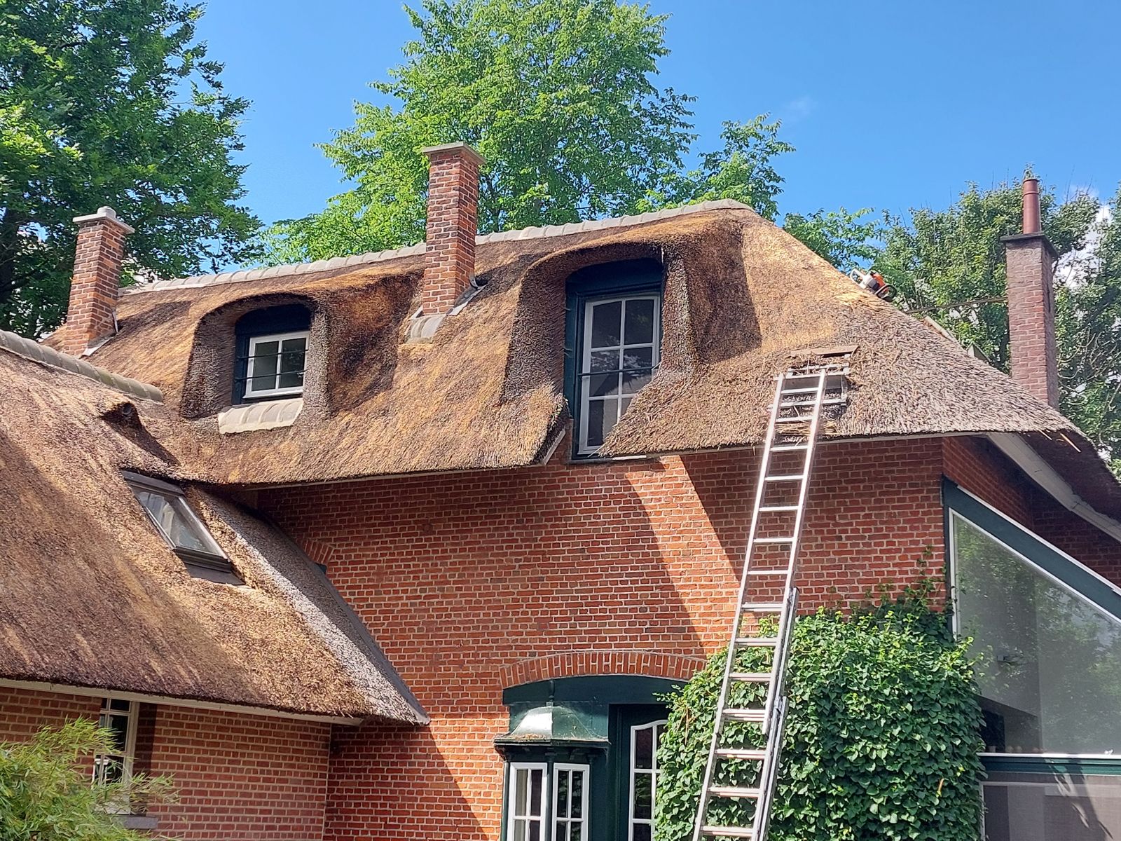 Rieten dak van een villa met dakkapellen tijdens de renovatie