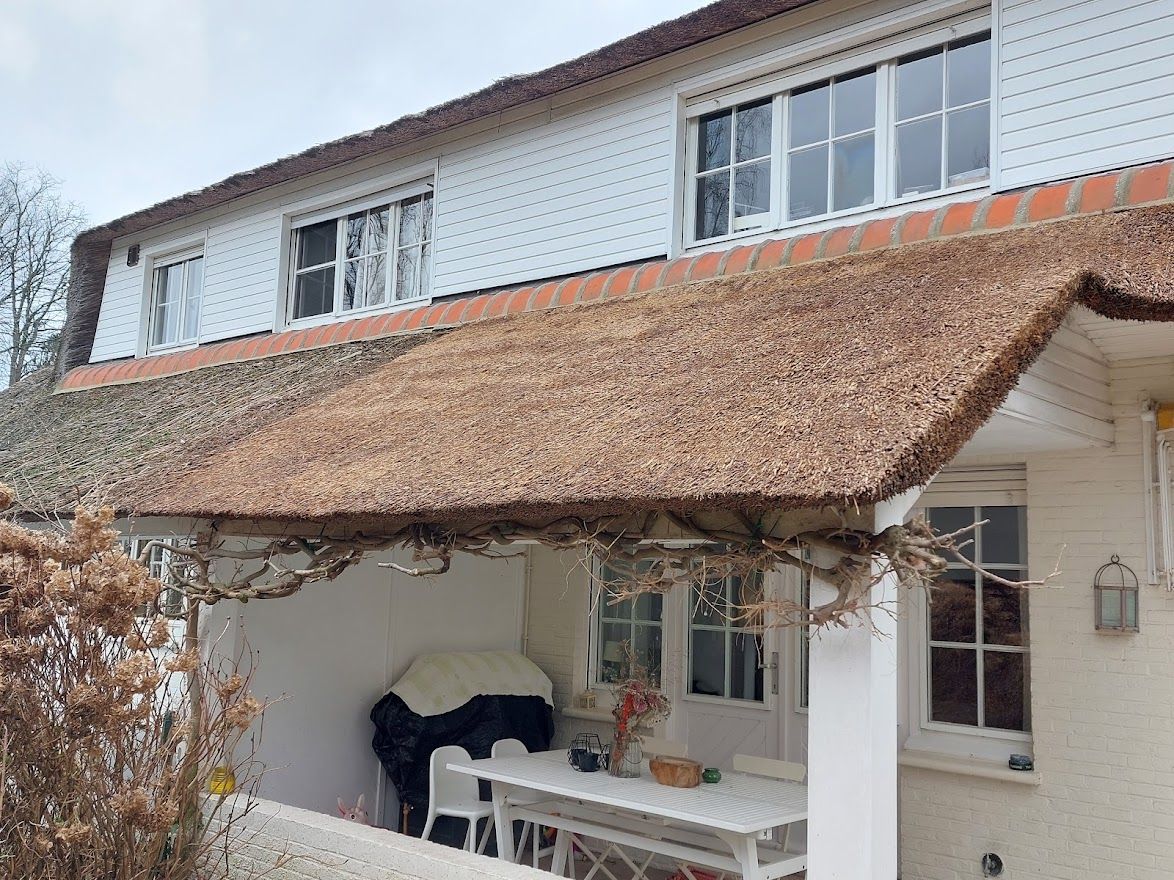 Rieten dak boven een terras van een witte woning